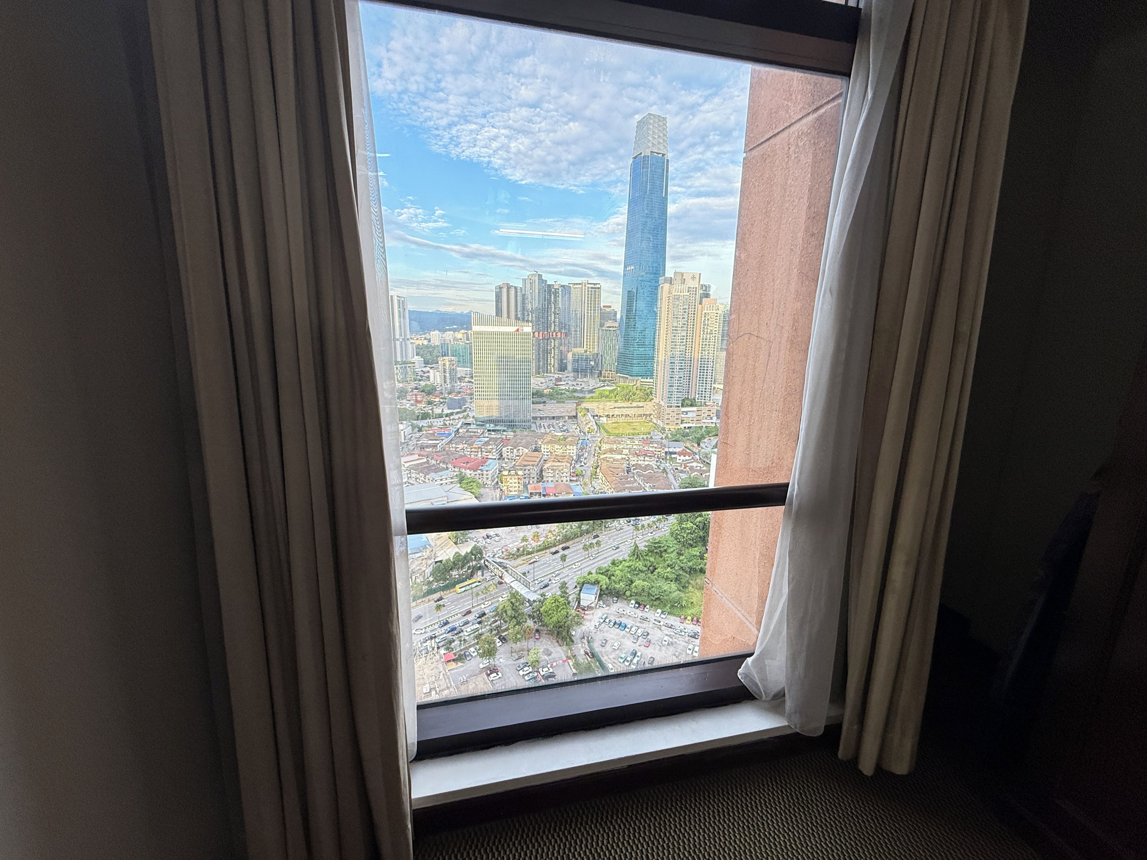 Una ventana con vista a un paisaje urbano, incluyendo edificios altos y una carretera.