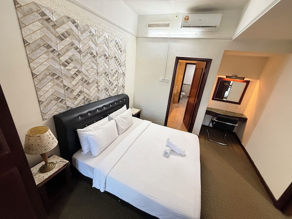 A hotel room with a bed, a nightstand, a lamp, a mirror, and a bathroom visible through an open door. - Times Square By Eas Maju (Kuala Lumpur)
