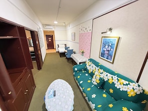 A room with a sofa, a small table, a cabinet, and a bed with a headboard. - Times Square By Eas Maju (Kuala Lumpur)
