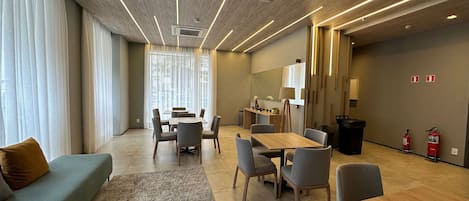 Una habitación de hotel moderna con comedor, sofá, alfombra y extintor.