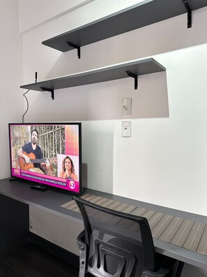 A television mounted on a wall with a desk and chair below. - TrevizZo São Caetano do Sul (São Caetano do Sul)