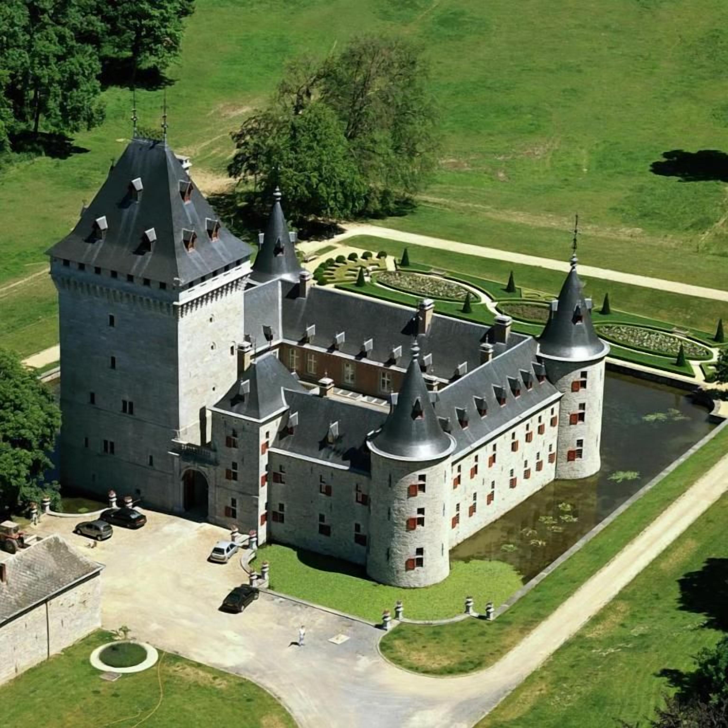 Un grand château doté de nombreuses tours et entouré de douves.