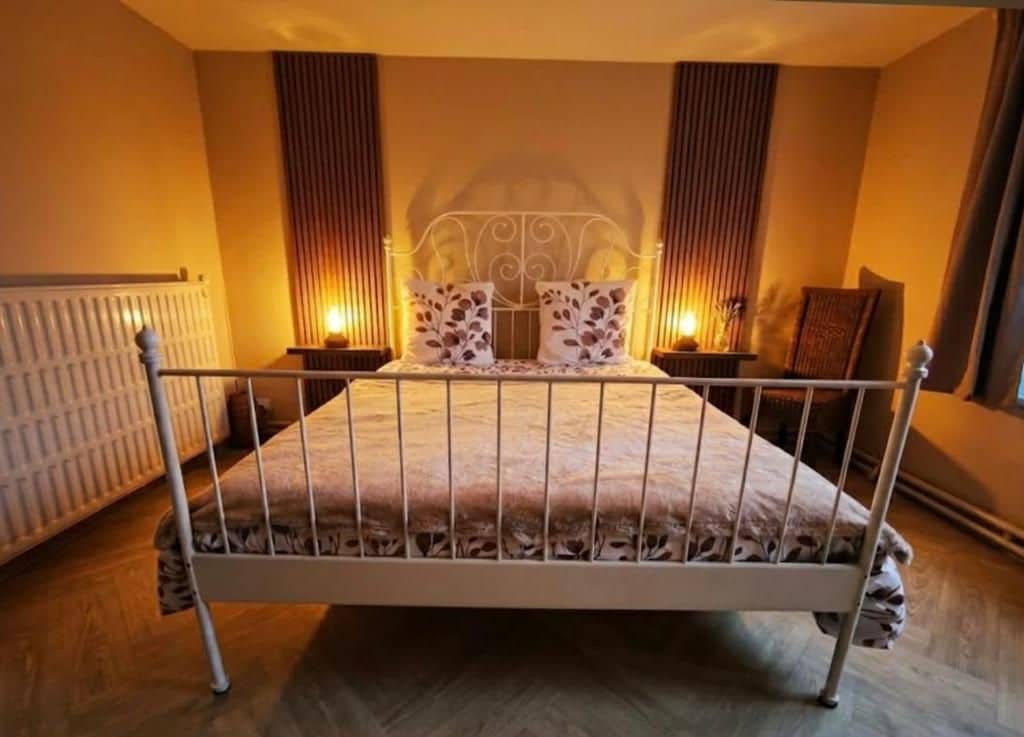 A bedroom with a metal-framed bed, two bedside tables, and a radiator.