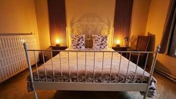 A bedroom with a metal-framed bed, two bedside tables, and a radiator.