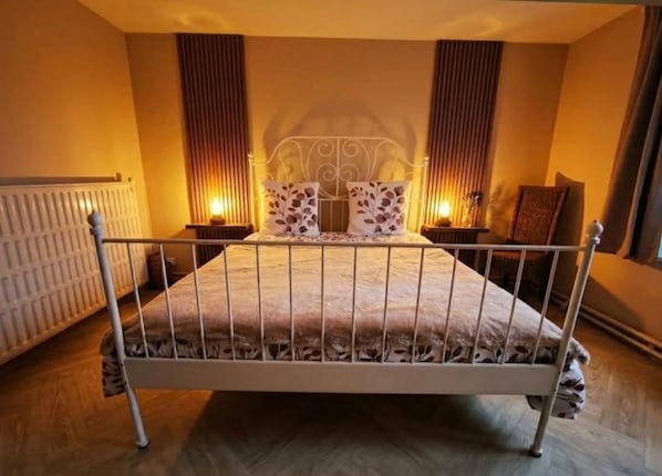 A bedroom with a metal-framed bed, two bedside tables, and a radiator.