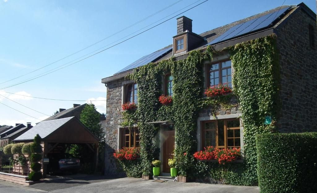 A stone building with ivy-covered walls and red flowers.
