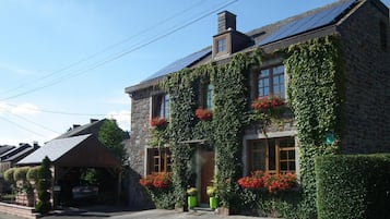 A stone building with ivy-covered walls and red flowers.