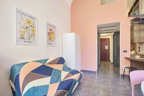 Een kamer met een bank, een koelkast en een kitchenette.