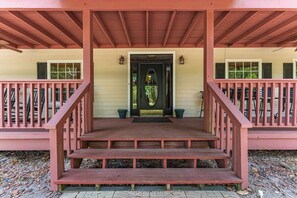 A wooden porch with a set of stairs leading to a door, surrounded by a railing.