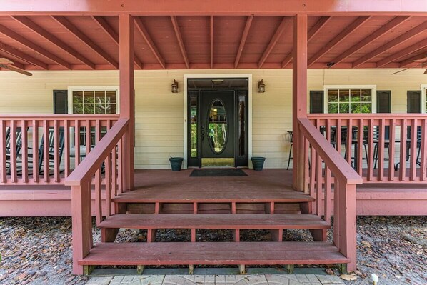 A wooden porch with a set of stairs leading to a door, surrounded by a railing.