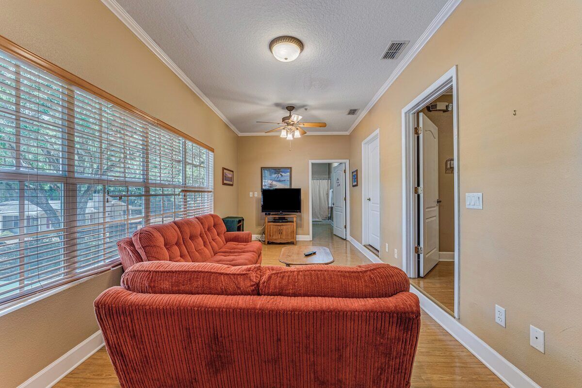 A living room with a large window, a ceiling fan, and a television.