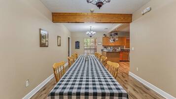 A dining room with a checkered tablecloth, wooden chairs, and a chandelier.