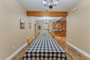 Une salle à manger avec une nappe à carreaux, des chaises en bois et un lustre.