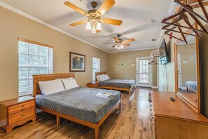 A hotel room with two beds, wooden floors, ceiling fans, a wooden dresser, and a large mirror.