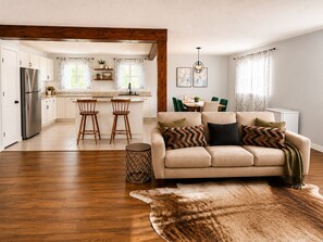 A modern kitchen with white cabinets, a stainless steel refrigerator, and a dining area with a table and chairs. - Spacious home, 10 min to wineries and many attractions. Free parking & wifi (Welland)