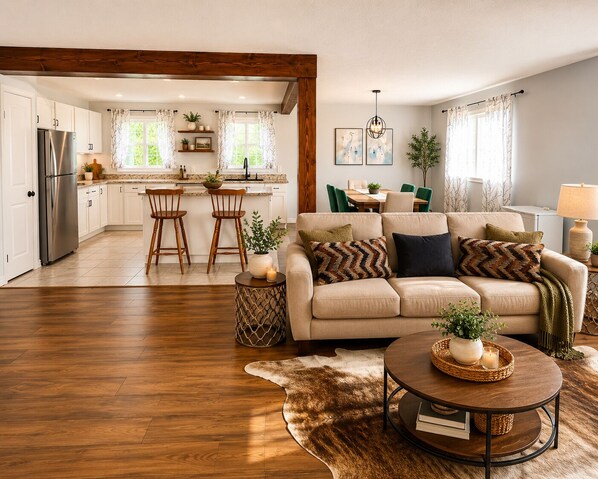 A modern living room with a sofa, a coffee table, and a dining area in the background. - Spacious home, 10 min to wineries and many attractions. Free parking & wifi (Welland)