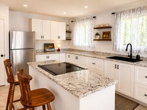 A kitchen with white cabinets, a stainless steel refrigerator, a black faucet, and a granite countertop. - Spacious home, 10 min to wineries and many attractions. Free parking & wifi (Welland)