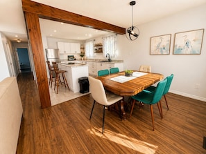 A dining area with a wooden table and chairs, a kitchen in the background, and a hallway leading to another room. - Spacious home, 10 min to wineries and many attractions. Free parking & wifi (Welland)