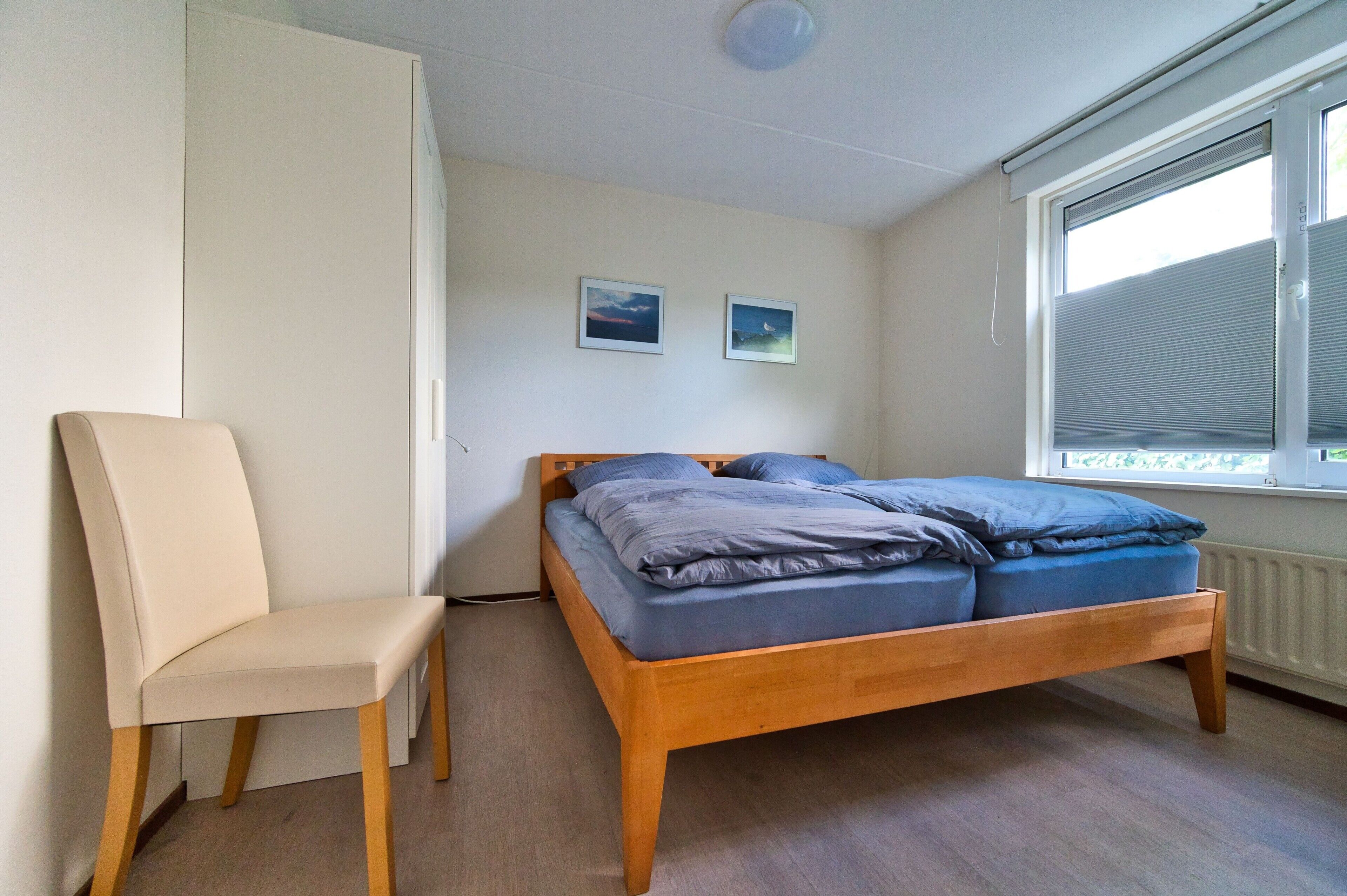 Een slaapkamer met een bed, een stoel en een raam.