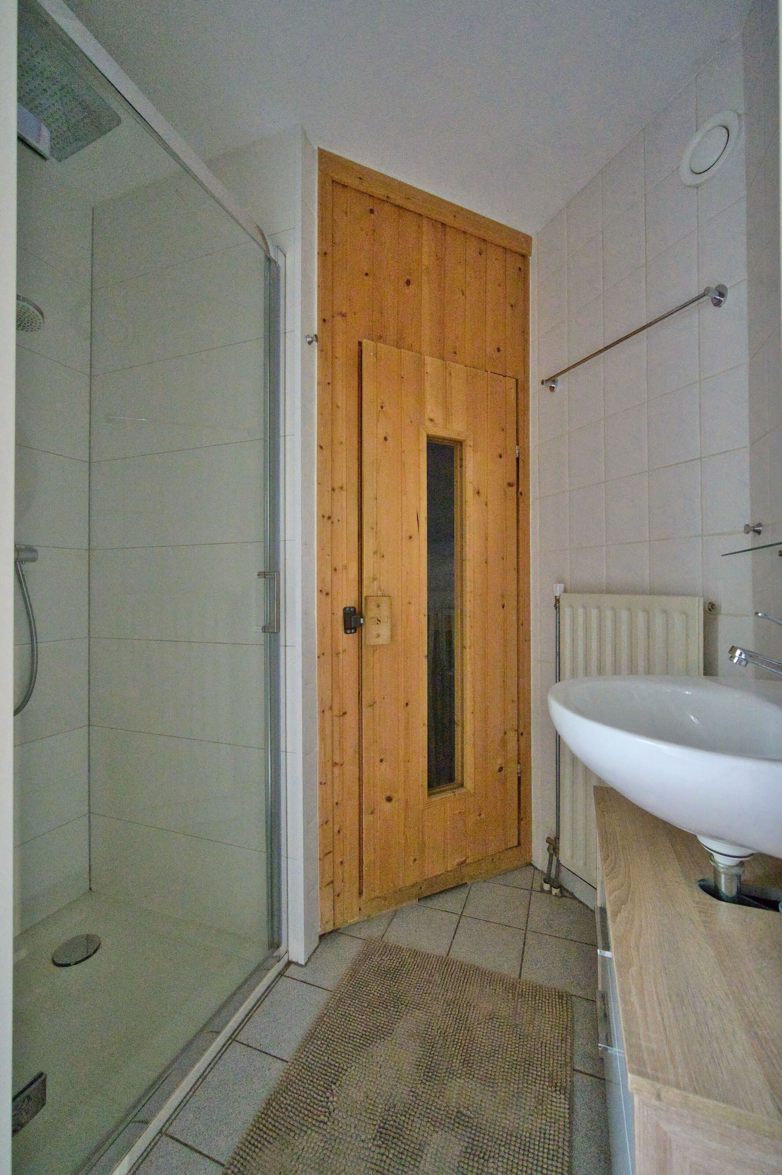Une salle de bain avec une porte en bois, une douche et un lavabo.