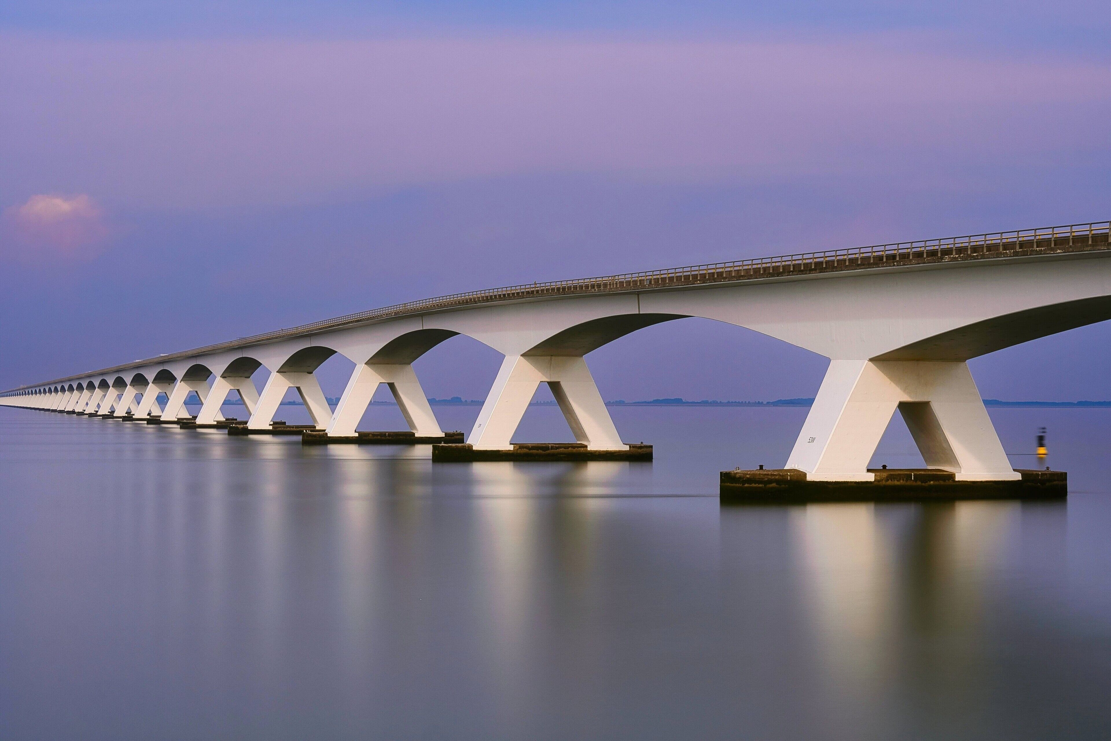Een lange brug met meerdere bogen over een kalm waterlichaam.