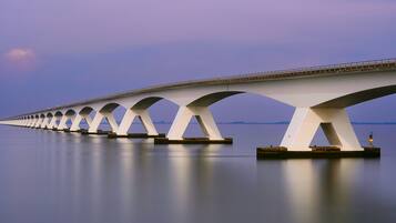 Een lange brug met meerdere bogen over een kalm waterlichaam.
