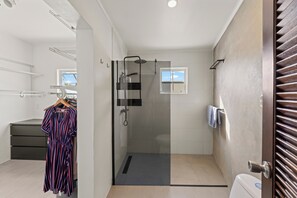 A modern bathroom with a glass-enclosed shower, a toilet, and a small window. - Luxury Apartment Nestled in Beautiful Natural Surroundings (Willemstad)