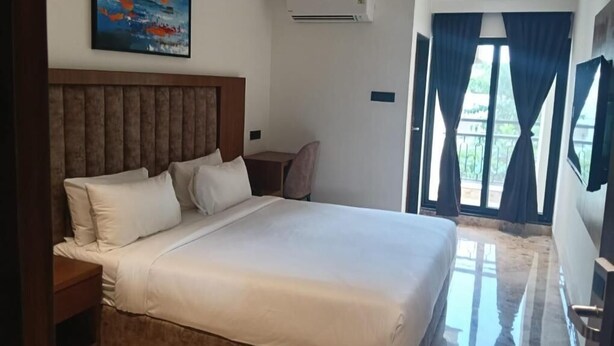 Habitación de hotel con una cama grande, cabecero, mesita de noche y un cuadro en la pared, además de una ventana con cortinas.