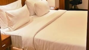 Una habitación de hotel con cama, mesita de noche, lámpara y escritorio con silla.