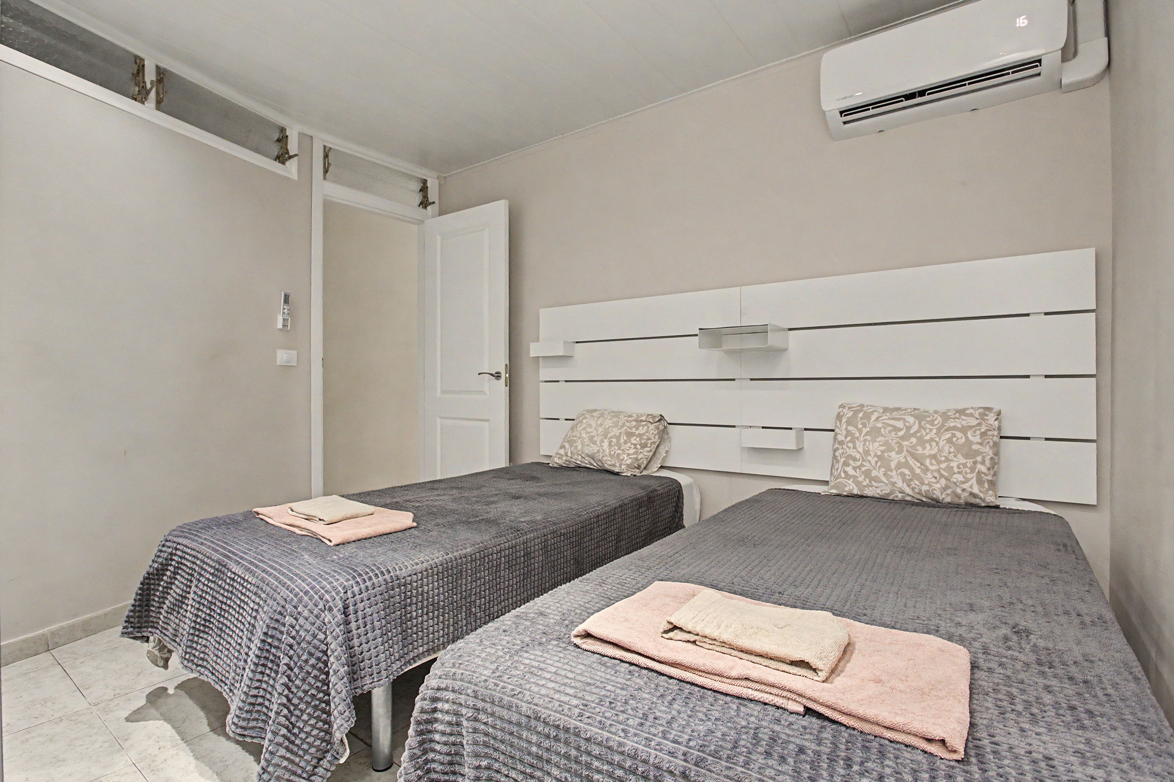 Un dormitorio con dos camas, un armario y un equipo de aire acondicionado.