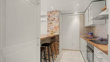 Una cocina moderna con una pared de acento de piedra, taburetes de bar y un horno empotrado.
