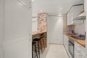 A modern kitchen with a stone accent wall, bar stools, and a built-in oven. - Vacation Apartment 'By The Sea in Los Cristianos' with Wi-Fi and Air Conditioning (Los Cristianos)