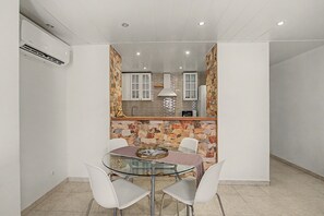A compact kitchen with stone accents, a glass-top dining table with chairs, and a microwave on the counter. - Vacation Apartment 'By The Sea in Los Cristianos' with Wi-Fi and Air Conditioning (Los Cristianos)