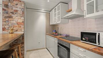 Cocina compacta con pared de acento de piedra, microondas y horno empotrado.