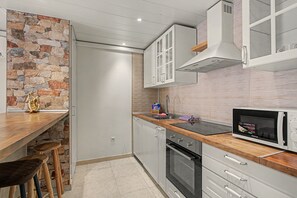 Cocina compacta con pared de acento de piedra, microondas y horno empotrado.