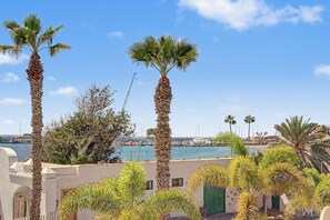 A coastal view with palm trees, a marina, and a building with a green door. - Vacation Apartment 'By The Sea in Los Cristianos' with Wi-Fi and Air Conditioning (Los Cristianos)