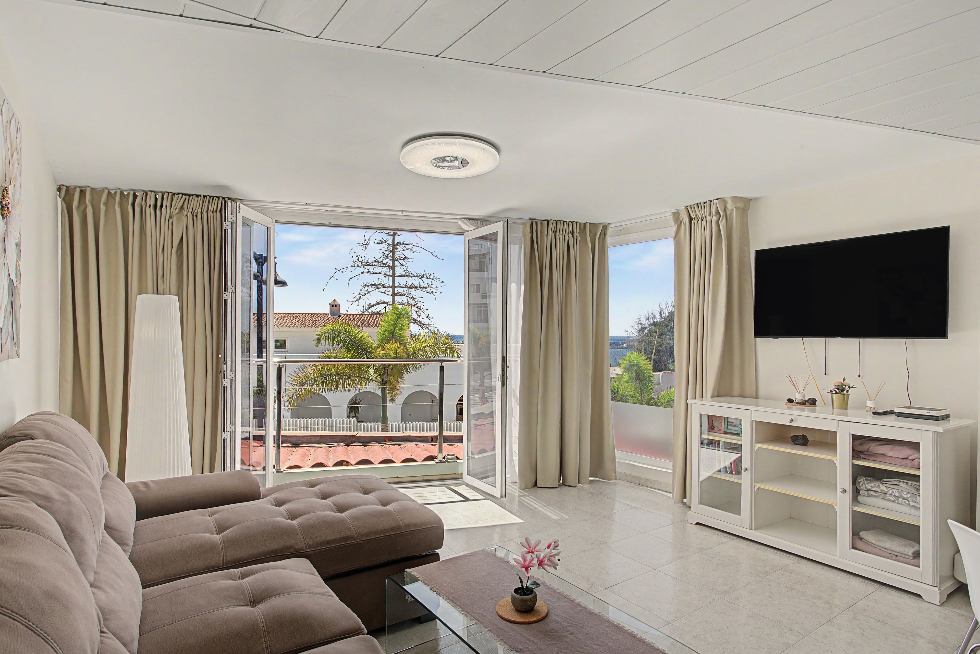 Een moderne woonkamer met een bank, een televisie en een balkon met uitzicht.
