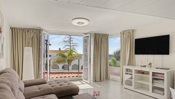 Een moderne woonkamer met een bank, een televisie en een balkon met uitzicht.