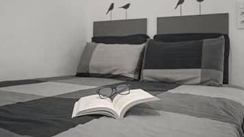 A bed with a book and glasses on it, a pillow, and a headboard with two bird decorations.