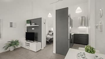 Un espace de vie moderne et minimaliste, doté d’un téléviseur à écran plat, d’une petite plante et d’un coin repas avec une table et des chaises.