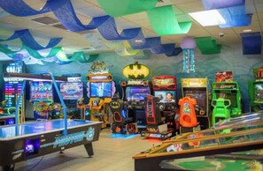 Eine Indoor-Spielhalle mit verschiedenen Spielautomaten, darunter ein Billardtisch und Greifklauenmaschinen.
