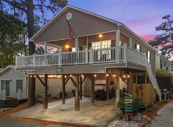 A two-story house with a balcony, a garage, and a covered porch area. - Tico Taco ya ya ya in Ocean Lakes Campground- golf cart + linens included (Myrtle Beach)