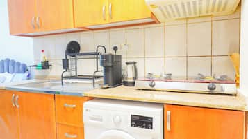 Une cuisine compacte équipée d’un lave-vaisselle, d’une machine à café et d’une cuisinière.