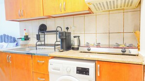 Une cuisine compacte équipée d’un lave-vaisselle, d’une machine à café et d’une cuisinière.