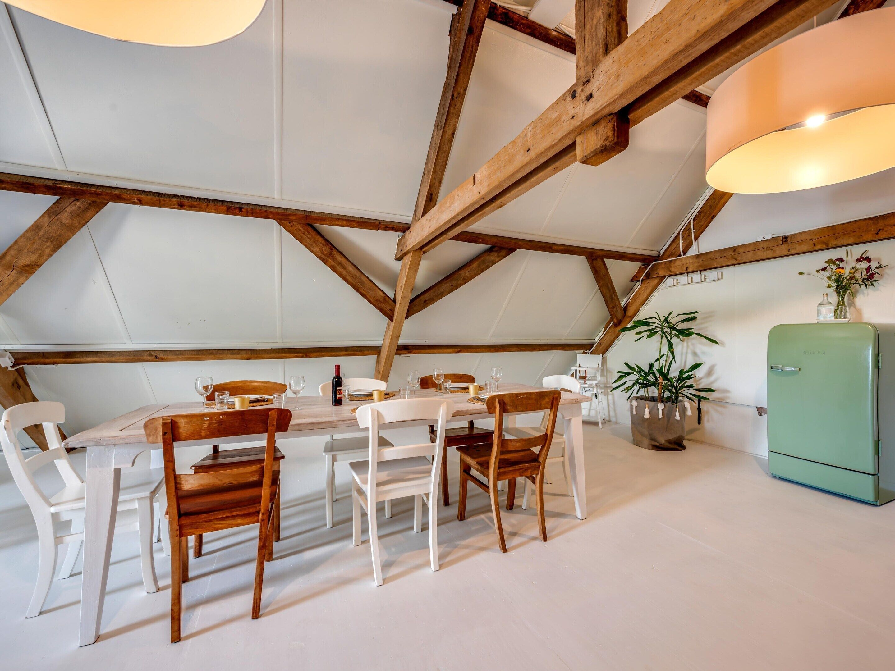 Un coin repas avec une table et des chaises en bois, un réfrigérateur vert et une plante en pot.