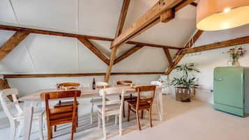 Un coin repas avec une table et des chaises en bois, un réfrigérateur vert et une plante en pot.