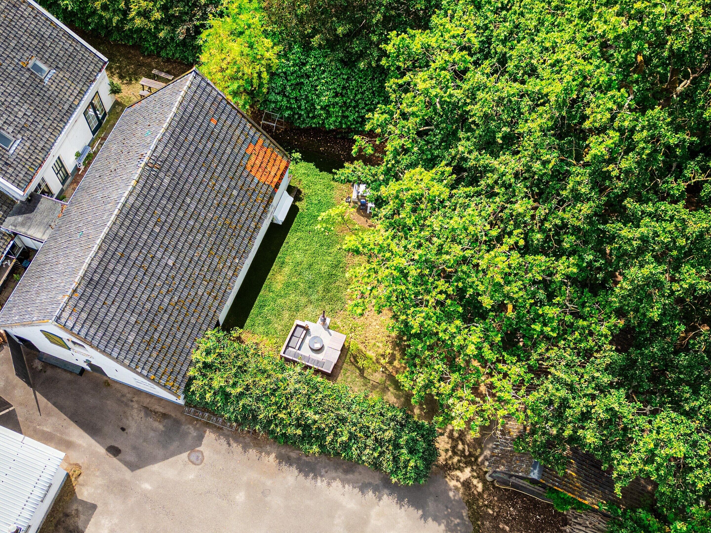 An aerial view of a residential area with a house featuring a sloped roof and a small garden area.