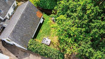 An aerial view of a residential area with a house featuring a sloped roof and a small garden area.
