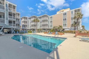 A pool area with lounge chairs and a clear blue pool. - Beach Access 2-bedroom condo with AC in North Myrtle Beach (North Myrtle Beach)