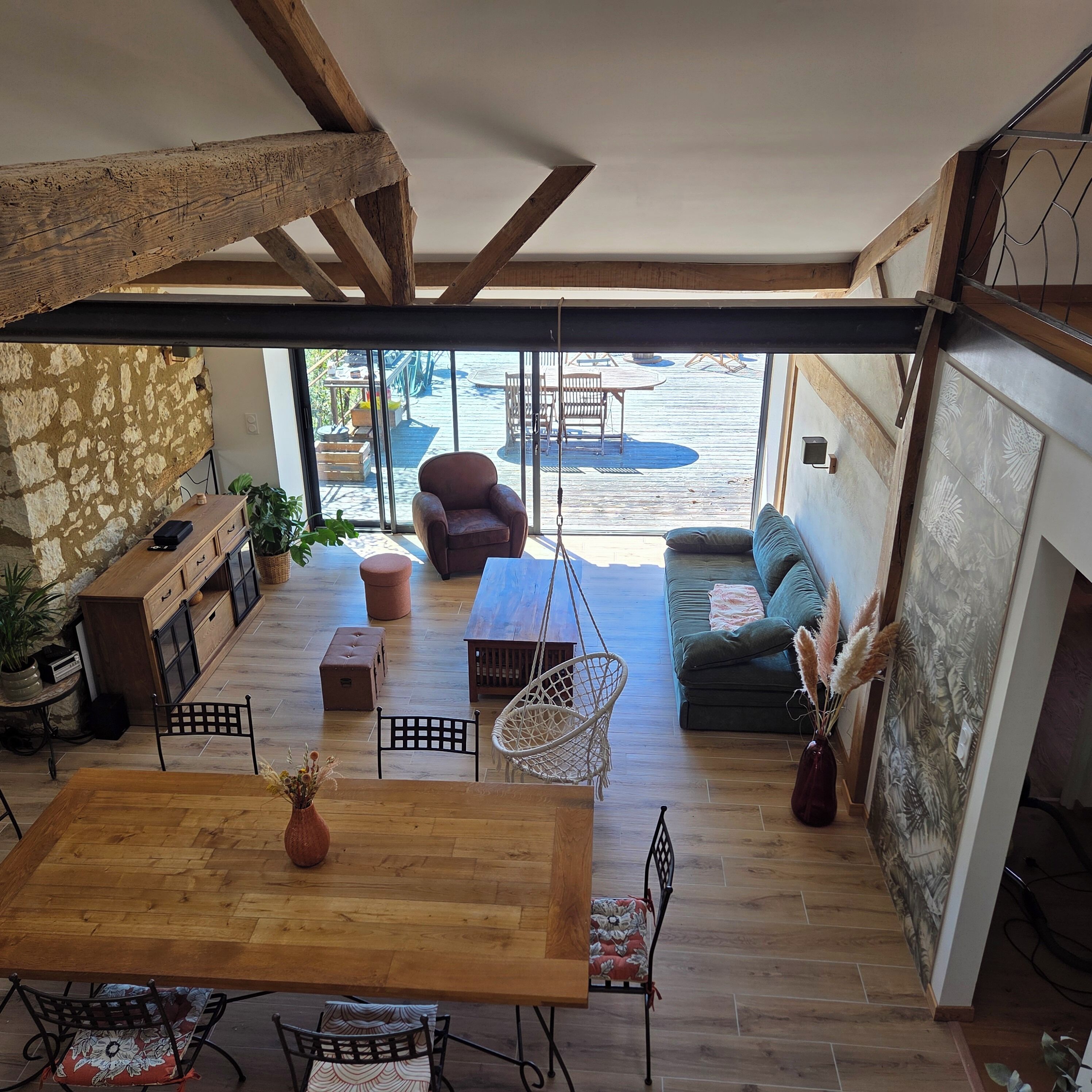 An open-plan living space with a wooden dining table, seating area, and a view to an outdoor patio.